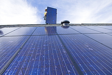 A worker installs solar panels on a rooftop in Redmond, WA.