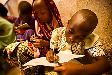 Rwandan girls completing their school work on the school room floor.