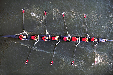 An aerial perspective of a crew of women rowers in a boat crewing down the Tennessee River at sunset.