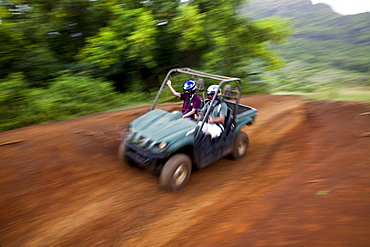 A couple race around a tight corner in an ATV while partaking in an off-road adventure.