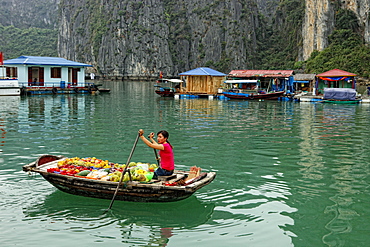 A fruit vendor paddles boxes of product in Halong Bay, Vietnam.