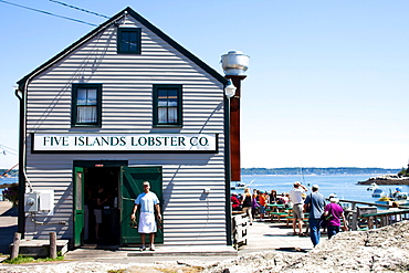 A man holds freshly caught lobster outside his dockside food stand.