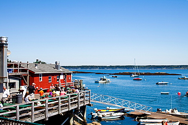 Crowds sit at picnic tables and enjoy the views of the harbor below.