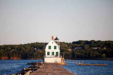 A lighthouse sits at the edge of a large, rocky dyke.