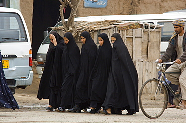 Tajik girls wear full length Iranian style veils, called "abbaya" as they walk to school through the bazaar of  Turghondi, a town on the border with Turkmenistan, in the northern part of Herat Province.