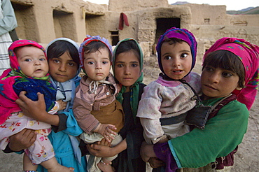 Young girls hold infant siblings in their home compound, in the Tajik village of Dera Jawal, at the base of the Band-e Baba range,  Herat Province, Afghanistan