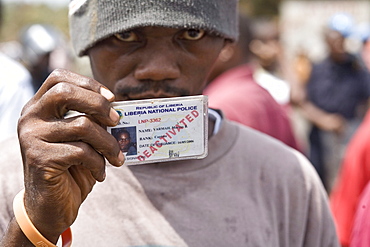 Young man holding up his deactivated Police ID card. Former members of the Armed forces of Liberia and Liberian Nation Police block the road at EWA junctions demanding the President pay back payments for the years they were not paid under the Taylor regime. The protest ended in violence with tear gas being firied on the crowd.