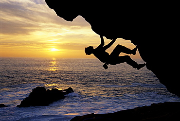 Kevin Jorgesen bouldering at sunset on the craggy Sonoma County coastline in Northern California. Bouldering is a kind of  gymnastic rock climbing in which the climber uses his hands and feet to scale reasonably small rocks without a rope or other equipment.