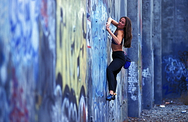 Sabina Allemann buildering on a graffiti covered wall in San Jose, California.