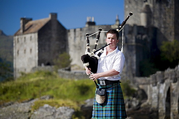 A young man plays scottish bagpipes in Eilean Donan Castle, Dornie, Scotland, United Kingdom, August 2007