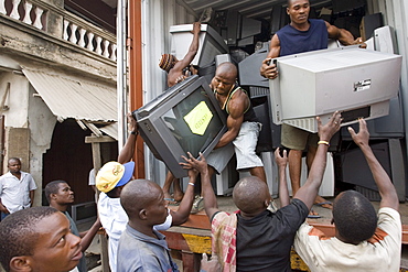 Workers unload televisions at the Alaba Market, Lagos Nigeria. Many of the electronics here are second hand and shipped from Asia, the USA or Europe for reuse. The small shop dealers buy electronics from the containers and are very good at repairing the goods for sale. Only when material has no value is it sent to nearby dumps.