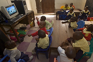 Yinka Ogunsuyi teaches a computer class to 9-11 year olds from the Regency School in Lagos, Nigeria. He gets the computers from a contact in the USA and also buys some in Nigeria. The computer is a Pentium 3 Dell from the USA. Also at the school 2-3 year olds watch the movie "Happy Feat" on a Pentium 4 computer.