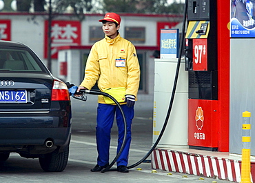 A Chinese gas station attendant fills up a customer's car in Beijing. Chinese Premier Wen Jiabao promised a national plan to address climate change but avoided offering emissions caps, speaking after a parliament session where global warming barely scraped onto the agenda.