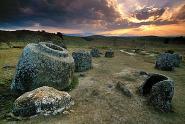 Plain of Jars, Central Laos - February 2003: A dramatic sunset forms a dramatic backdrop behind the mysterious Plain of Jars in central Laos. The stone jars are still an enigma for archeologists, who have dated the relics to the period between 500 BC and 800 AD. There are many theories as to what the jars were used for and how they were created, but none of the theories are considered definitive.