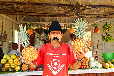 A fruit vendor holds pineapples at his fruit stand in the in the Vinales Valley, in the Pinar del Rio Province of Cuba. The Vinales Valley has been on UNESCO's World Heritage List since November 1999 as a cultural landscape enriched by traditional farm and village architecture. Old-fashioned farming methods are still used in Vinales, notably to grow tobacco.