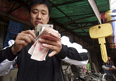 A man counts "Ren Min Bi", China's currency, which translates in to "The People's Money" in Songzhuang Village, in Beijing's eastern suburbs.