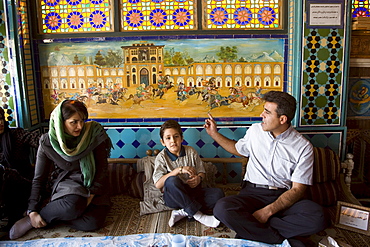 Esfahan, Iran - February, 2008: Iranian family having lunch in a colorful traditional looking restaurant on Imam Square in Esfahan, Iran.