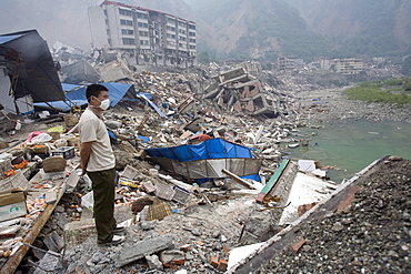 A man look out at Beichuan Town, which was severely damaged by a powerful 7.9 earthquake. The Chinese government raised the death toll to 21,500 but has said fatalities could rise above 50,000. Tens of thousands could still be buried in collapsed buildings in Sichuan province, where the quake was centered.