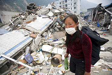 A woman walks through the rubble of Beichuan Town, which was severely damaged by a powerful 7.9 earthquake. The Chinese government raised the death toll to 21,500 but has said fatalities could rise above 50,000. Tens of thousands could still be buried in collapsed buildings in Sichuan province, where the quake was centered.