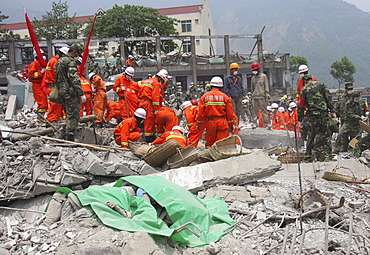 A green plastic sheet covers bodies at the scene of destruction at a middle school in Beichuan Town. The Chinese government raised the death toll to 21,500 but has said fatalities could rise above 50,000. Tens of thousands could still be buried in collapsed buildings in Sichuan province, where the quake was centered,