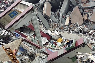 A man is dwarfed by the wreckage of Monday's earthquake in Beichuan Town. The Chinese government raised the death toll to 21,500 but has said fatalities could rise above 50,000. Tens of thousands could still be buried in collapsed buildings in Sichuan province, where the quake was centered.