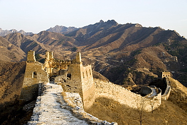 Beautiful view of Great Wall looking east near Simatai. The wall continuing up over steep inclines on mountain ridges in distance.