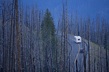 A camper and car travel through Yellowstone National Park in Wyoming.