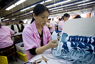 A woman inspects the quality of a batch of blue bras in the Top Form factory in Longnan, China.