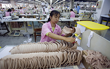 A woman inspects the quality of a batch of flesh colored bras in the Top Form factory in Longnan, China.