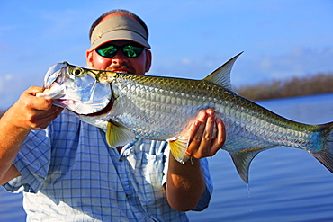 A fly fisherman with a small tarpon that caught with a fly rod on Great Inagua in the Bahamas.