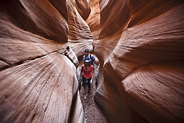 A couple hiking through a slot canyon in Utah.