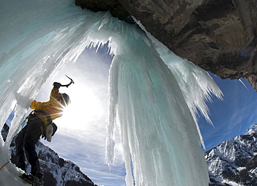 A man wields his ice ax while ice climbing a frozen waterfall near Ouray, Colorado. (solar flare)