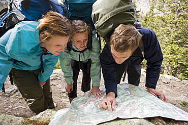 Two women and a man read a map while backpacking in the backcountry of Rocky Mountain National Park, Colorado.