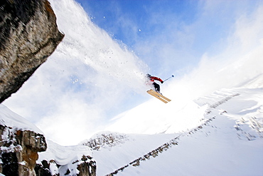 A male skier jumps off a cliff while skiing in the Wyoming back country.