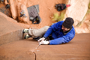 A male climber climbs a route in Indian Creek called Burl Dog in Utah.