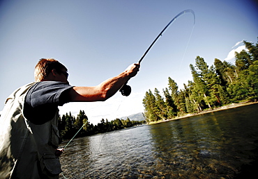 A teenage boy fly fishing in Swan River near Bigfork, Montana.