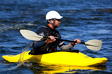 A male kayaker in a playboat paddles on the Clark Fork River, Missoula, Montana.