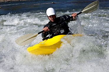 A male kayaker in a playboat paddles on the Clark Fork River, Missoula, Montana.