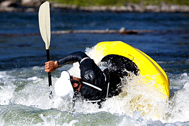 A male kayaker flips in a playboat rides the rapids of Brennan's Wave, Missoula, Montana.