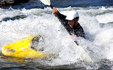 A male kayaker in a playboat battles the rapids of Brennan's Wave, Missoula, Montana.