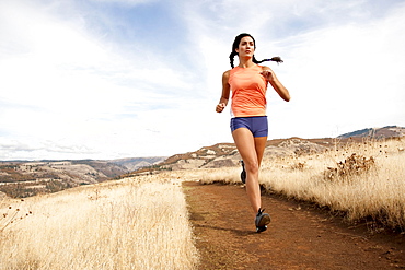 An athletic female jogs on a  dirt trail on an autumn day.