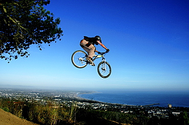 A young man goes off a jump on a mountain bike in the hills overlooking Ventura, California.