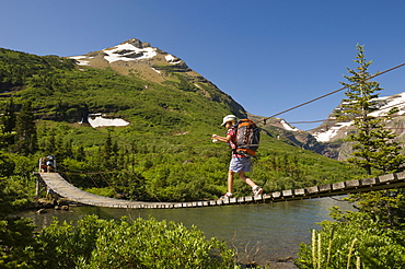 A young girl hikes over a suspension bridge in Glacier National Park, Montana.