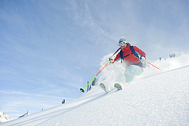 A woman skier smiles as she skis the powder in the backcountry of the Selkirk Mountains, Canada.