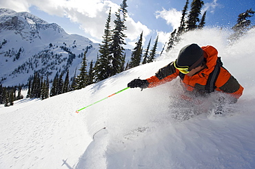 A young man skier skis the deep powder in the backcountry of the Selkirk Mountains, Canada.