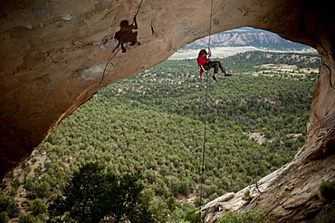 Young adult male rappels down an arch in Colorado.