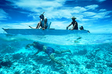 Polynesian men collect shells from an outrigger on Tubuai Island, French Polynesia