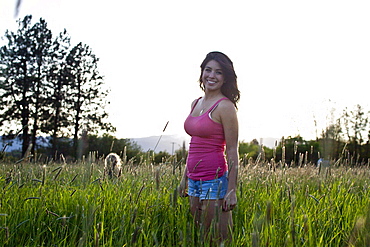 A girl stands in tall grass on a sunny day in Idaho.