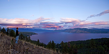 A male hiker watches the sunset over a lake in Idaho.