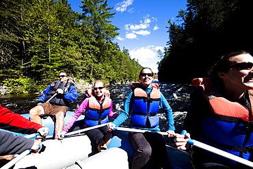 A group of adults whitewater rafting in Maine.